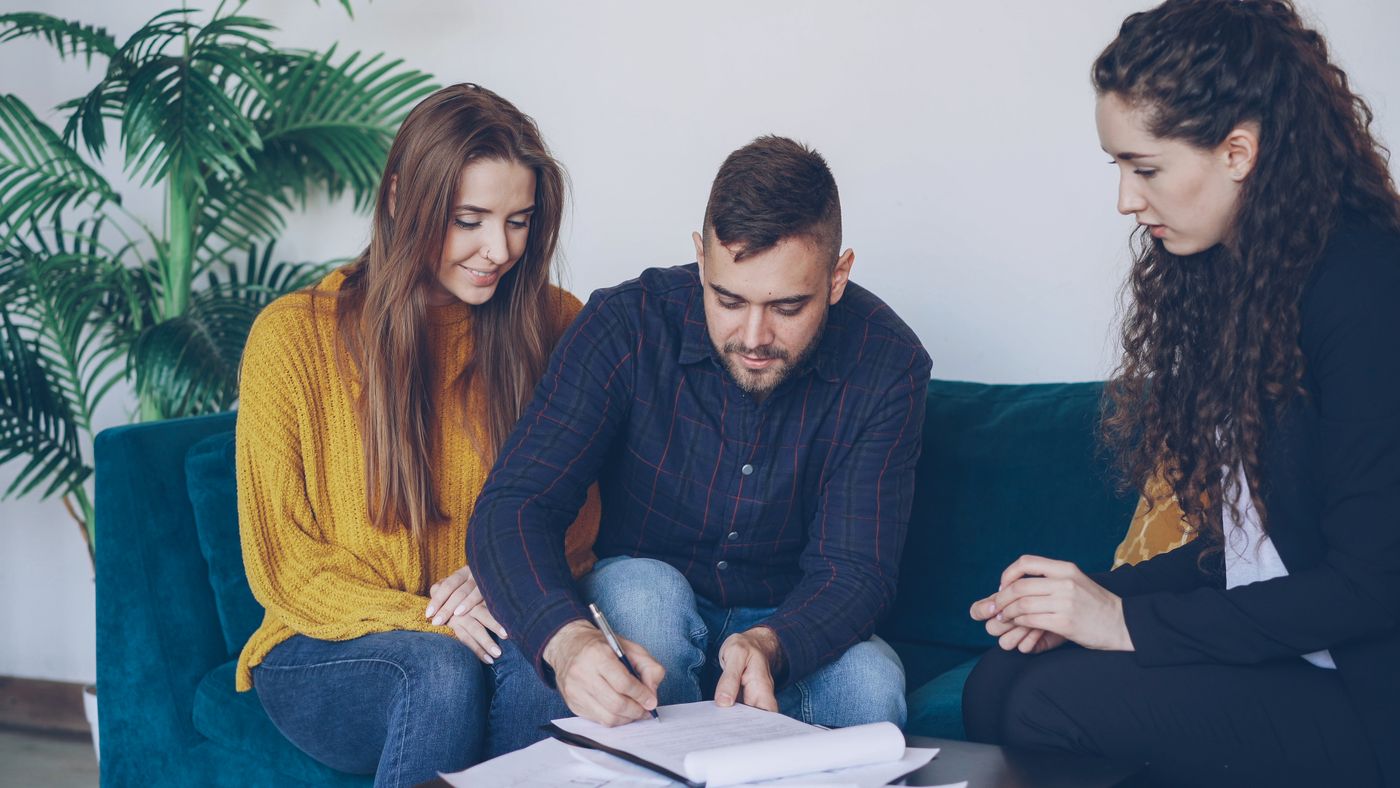 A couple signing paperwork with an advisor